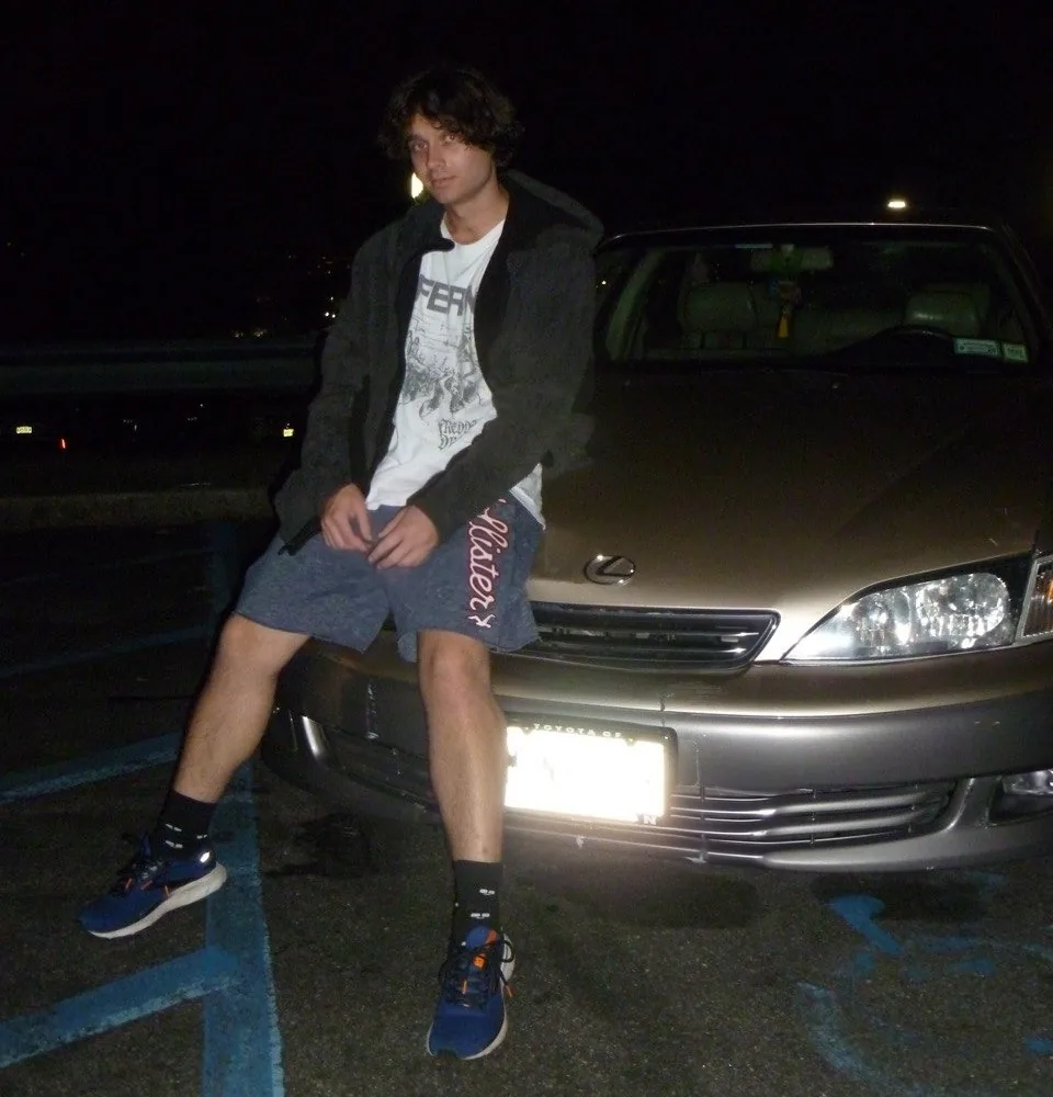 Artem Sumin sitting on the hood of his 2000 Lexus ES300 at night